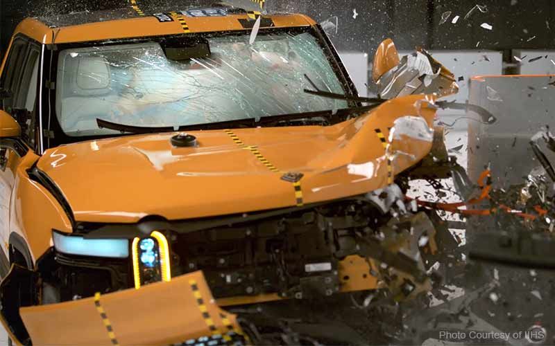 Orangenes Fahrzeug, das in einem Crashtest vorne links auf einen Betonklotz aufschlägt