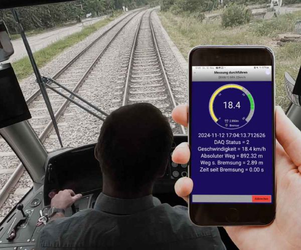 Führerstand einer Stadtbahn mit Fahrer und ein Hand mit Smartphone. auf dem die App zur Bremsweg-Messung von TMX läuft