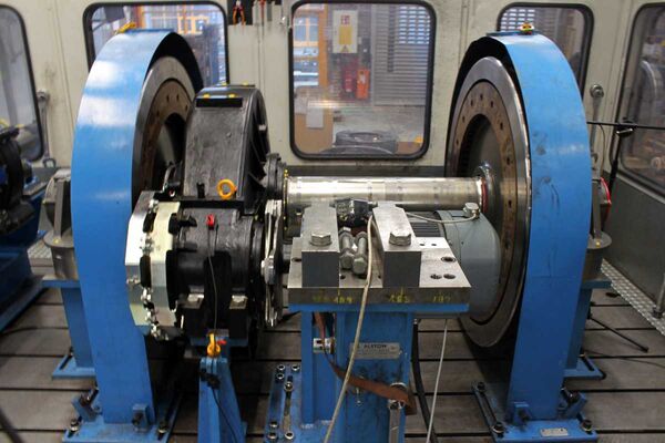 Blaues Prüfstandsgestell mit einem eingespannten Bahnradsatz mit Motor
